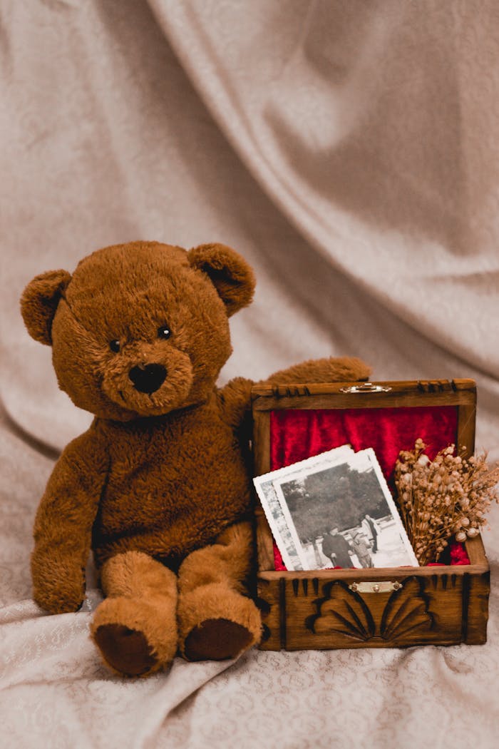 A nostalgic scene featuring a teddy bear and vintage photos in a wooden box.