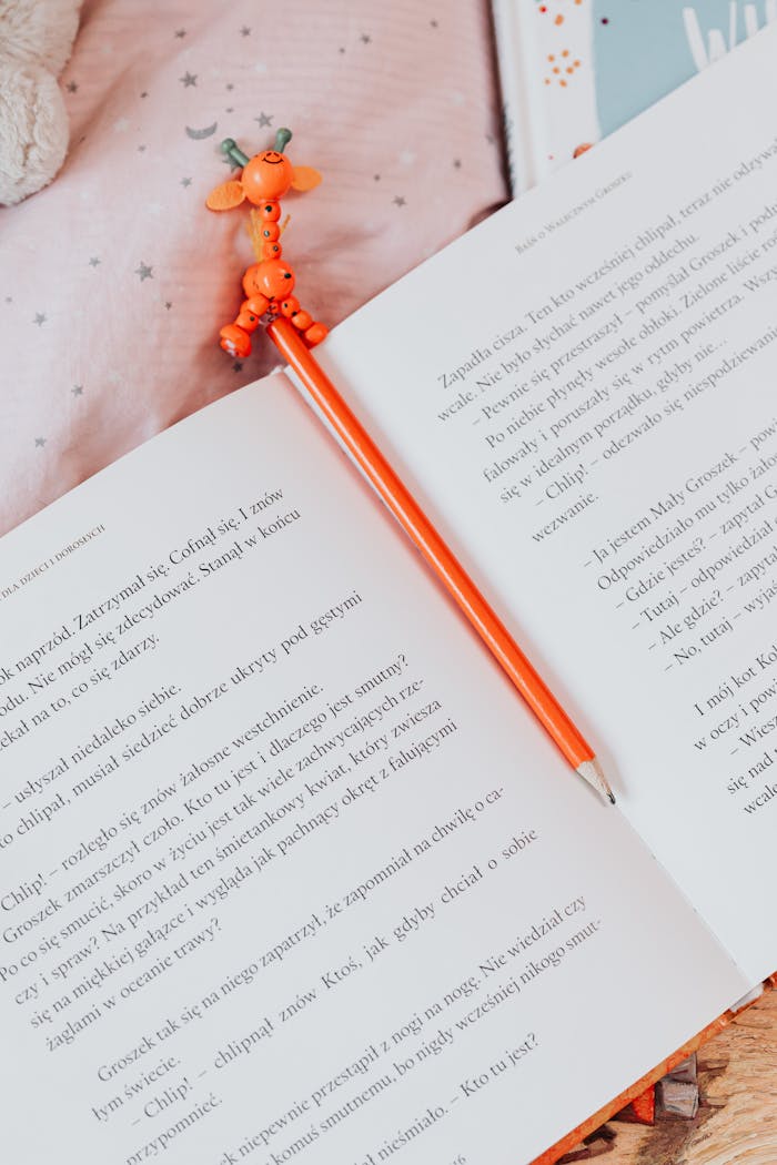An open book with an orange pencil featuring a giraffe topper, perfect for education and creativity.